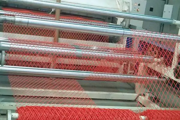عکس توری پلاستیکی که دور رول قرمز رنگ خط تولید توری پلاستیکی پیچیده شده است.