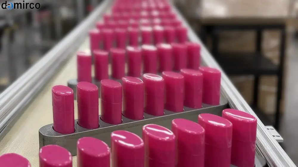 ماشین‌آلات صنعتی دمیرکو در حال تولید و بسته‌بندی رژ لب در یک خط تولید مدرن.