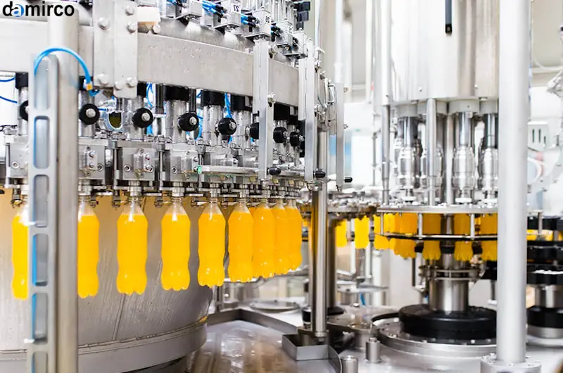 دستگاه درب بند تشتکی اتوماتیک در حال بستن درب فلزی بطری‌های نوشابه در یک کارخانه بزرگ