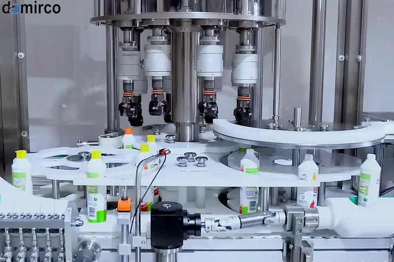 نمایی نزدیک از یک دستگاه درب بند اتوماتیک در حال بستن درب بطری‌های متعدد روی نوار نقاله در یک کارخانه مدرن