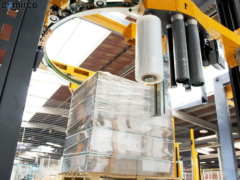 دستگاه استرچ پالت در حال بسته بندی یک پالت کارتن در یک انبار بزرگ