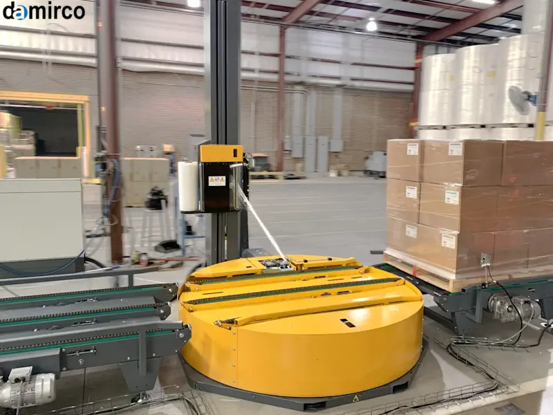 تصویر یک دستگاه استرچ پالت اتوماتیک در حال بسته بندی یک پالت بزرگ در یک انبار مدرن