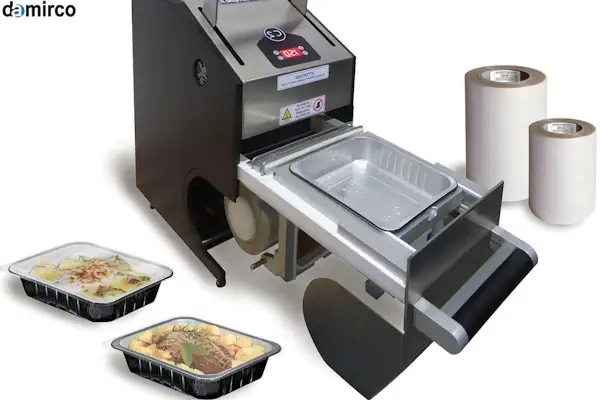 یک دستگاه سیل حرارتی رومیزی در حال بسته‌بندی بهداشتی ظرف غذا در یک کارگاه کوچک