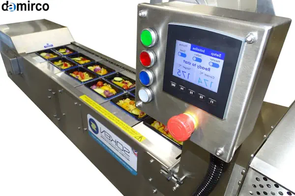 تصویر یک دستگاه سیل حرارتی اتوماتیک در حال بسته‌بندی ظروف مواد غذایی در یک کارخانه