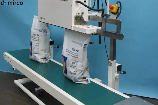 نمای نزدیک از دستگاه سیل ریلی در حال بسته‌بندی ظروف مواد غذایی روی نوار نقاله