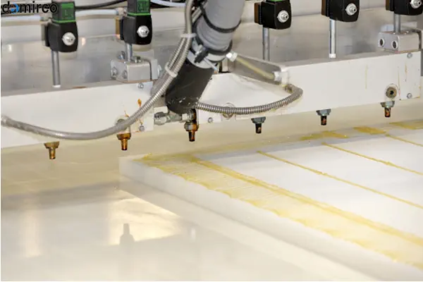 یک دستگاه چسب هات ملت صنعتی در حال چسباندن درب کارتن در یک خط تولید اتوماتیک بسته بندی