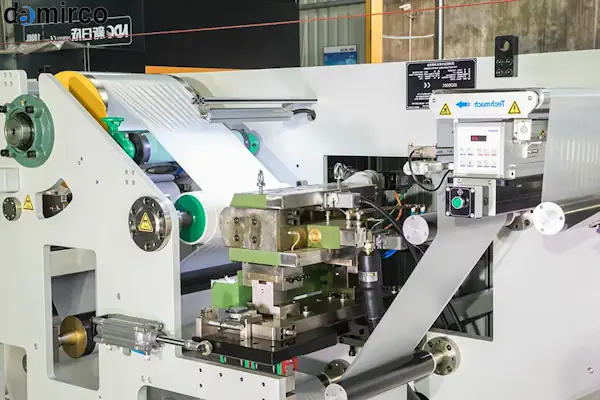 اپراتور با تجهیزات حفاظت فردی کامل در حال کار با دستگاه چسب هات ملت صنعتی