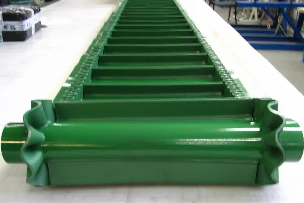 نمایی از یک نوار نقاله PVC سبز رنگ در حال حمل جعبه‌های مقوایی در یک کارخانه