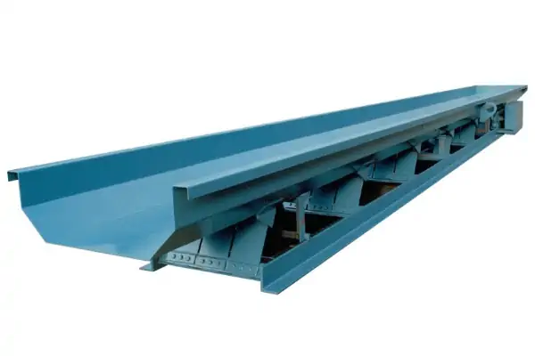 تصویری از یک کانوایر ارتعاشی صنعتی در حال انتقال مواد فله در یک کارخانه.