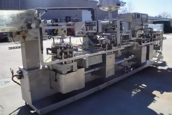 نمای نزدیک از عملکرد یک دستگاه ترموفیل سیل دست دوم در حال بسته‌بندی ظروف لبنی.