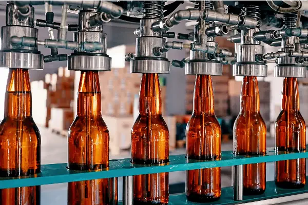 دستگاه خشک کن صنعتی در حال خشک کردن بطری های شیشه ای روی نوار نقاله پیش از ورود به بخش لیبل زنی