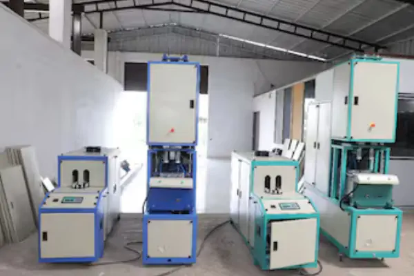 دستگاه بادکن پت اتوماتیک در حال تولید بطری‌های شفاف نوشابه در یک کارخانه صنعتی