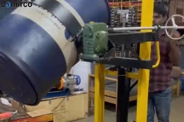 یک دستگاه بشکه گردان صنعتی با کیفیت در حال مخلوط کردن مواد داخل یک بشکه آبی رنگ در محیط کارخانه