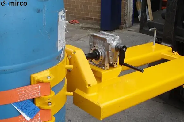 تصویر یک دستگاه بشکه گردان صنعتی آبی رنگ در حال چرخاندن یک بشکه فلزی در یک کارخانه