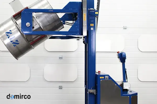 یک دستگاه بشکه گردان صنعتی زرد رنگ در حال چرخاندن یک بشکه آبی در یک محیط کارگاهی