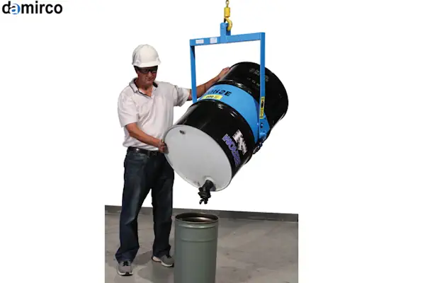 یک کارگر در حال استفاده از دستگاه بشکه گردان متحرک چرخدار برای جابجایی و تخلیه یک بشکه صنعتی در انبار