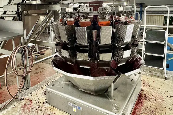 یک دستگاه بسته بندی توزین دار دست دوم در خط تولید یک کارخانه مواد غذایی