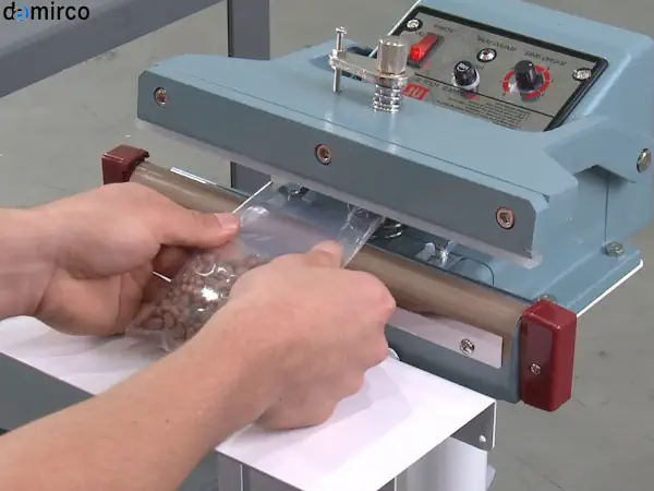 یک دستگاه دوخت پلاستیک پدالی صنعتی با بدنه فلزی در یک کارگاه تولیدی