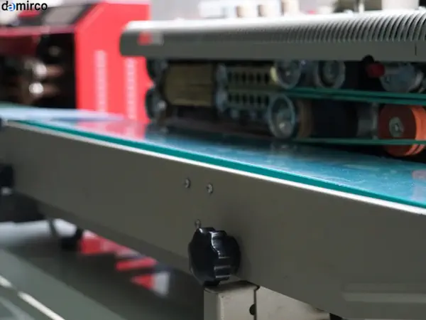 نمایی نزدیک از یک دستگاه دوخت پلاستیک صنعتی در حال بسته‌بندی یک محصول در خط تولید