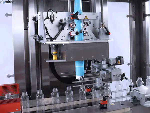 تصویر یک دستگاه لیبل شیرینگ بطری در خط تولید پیشرفته در حال لیبل زنی بطری های نوشیدنی