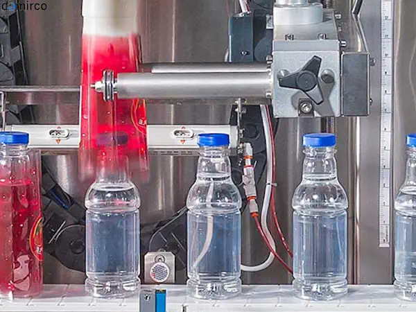 نمای نزدیک از نحوه کار دستگاه لیبل شیرینگ روی بطری‌های نوشیدنی