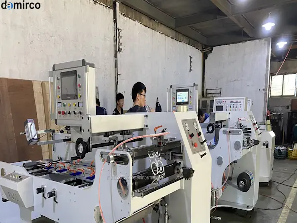 یک دستگاه لیبل شیرینگ رومیزی در حال کار بر روی بطری‌های کوچک نوشیدنی