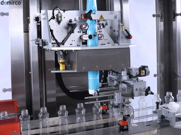 دستگاه لیبل شیرینگ در حال کار در یک خط تولید نوشیدنی مدرن