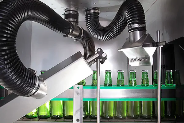 نمایی از یک دستگاه خشک کن بطری صنعتی که در حال خشک کردن بطری های شیشه ای روی نوار نقاله است.