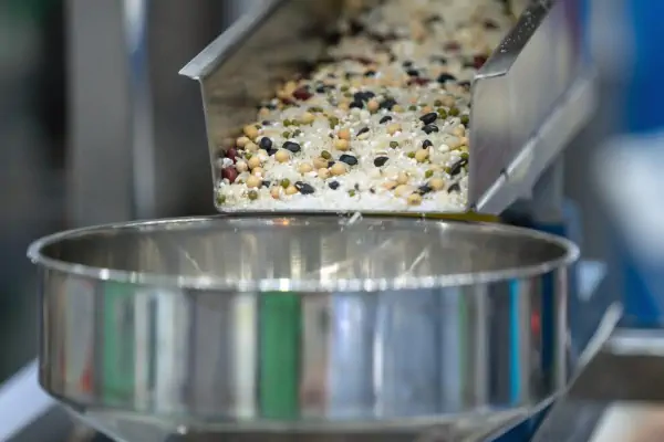 تصویر شماتیک یک انتقال دهنده ویبره در حال جابجایی مواد فله در یک کارخانه صنعتی، نمایش دهنده کاربرد انتقال دهنده ویبره.