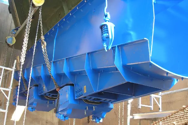 نمای نزدیک از یک انتقال دهنده ویبره الکترومغناطیسی در حال انتقال مواد گرانولی در یک خط تولید صنعتی.