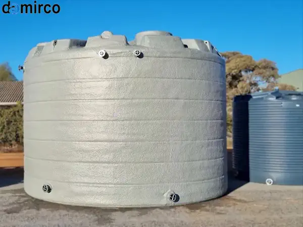 یک تانکر پلاستیکی 1000 لیتری سفید رنگ به شکل عمودی در یک محیط صنعتی