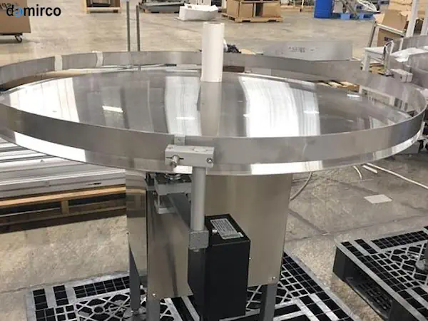 یک میز ترافیک صنعتی از جنس استیل در حال چرخاندن بطری‌های پلاستیکی در یک خط تولید