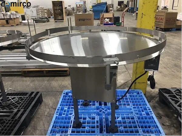 یک میز ترافیک صنعتی از جنس استیل ضد زنگ در حال جمع‌آوری بطری‌ها در یک خط تولید پیشرفته.