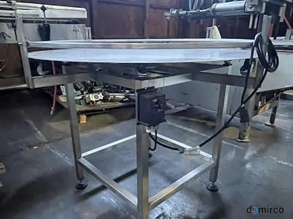 تصویر یک میز گردان بسته بندی استیل در حال کار در یک کارخانه مواد غذایی