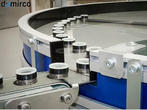 یک میز ترافیک بسته بندی دایره ای از جنس استیل که در حال مدیریت جریان بطری ها در یک خط تولید است