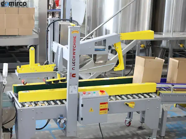 اپراتور در حال تنظیم دقیق دستگاه چسب زن کارتن در یک کارخانه صنعتی