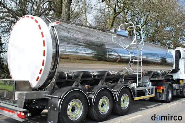 تصویر یک تانکر حمل شیر استیل ضد زنگ در حال تخلیه شیر در کارخانه لبنیات