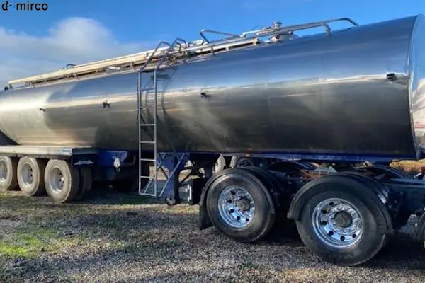 یک تانکر حمل شیر بزرگ از جنس استیل ضدزنگ که در کنار یک مزرعه لبنی پارک شده است