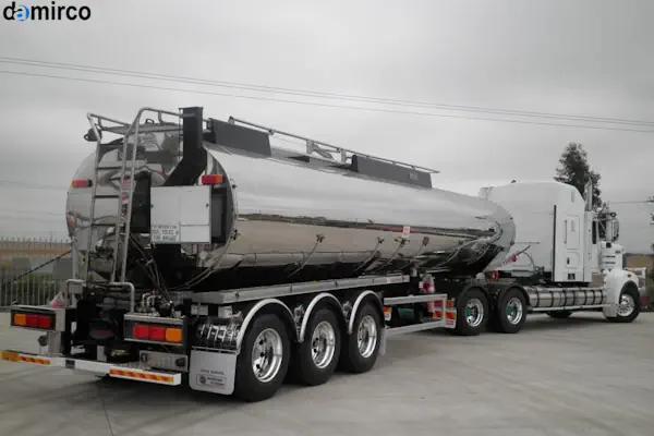 تصویر یک تانکر حمل شیر نیسان سفید رنگ مجهز به مخزن استیل در یک محیط روستایی