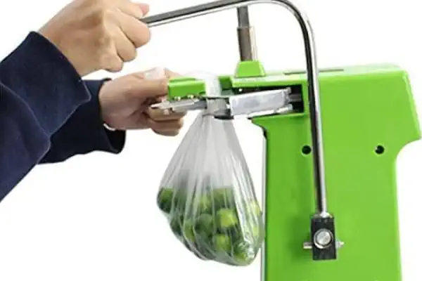 تصویر یک اپراتور در حال آموزش و کار با دستگاه کلیپس زن صنعتی در یک کارخانه تولید فرآورده‌های گوشتی.