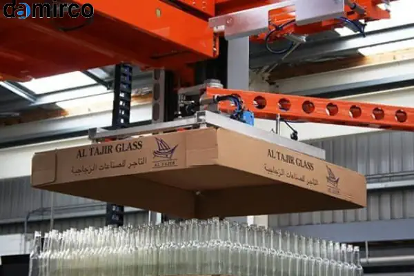 یک دستگاه پالتایزر رباتیک در حال چیدن منظم کارتن‌ها روی پالت در یک کارخانه مدرن