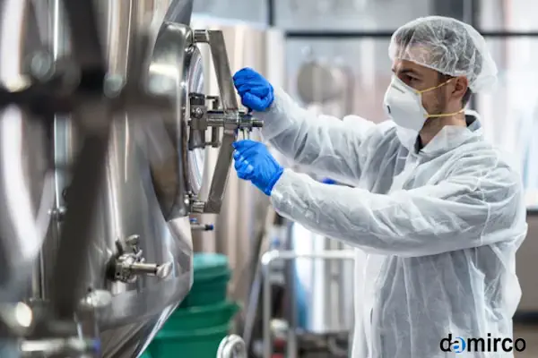 تصویری از یک میکسر مایعات صنعتی استیل در یک مخزن بزرگ در یک کارخانه تولید مواد شیمیایی.