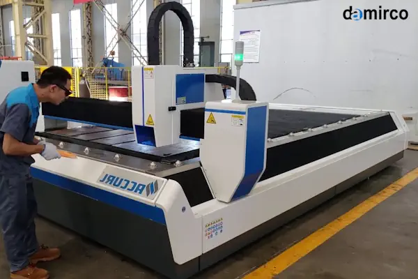 یک تکنسین در حال بررسی و عیب یابی بخش هد یک دستگاه برش لیزر صنعتی.