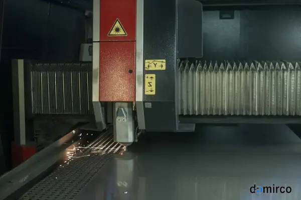 یک دستگاه برش لیزر فایبر در حال برش دقیق یک ورق فلزی در یک محیط صنعتی