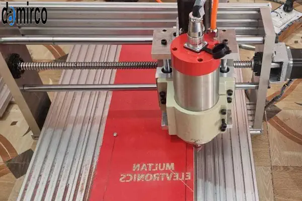 یک دستگاه حکاکی لیزری کوچک خانگی در حال حکاکی یک طرح خلاقانه روی یک قطعه چوب برای کسب درآمد در منزل.