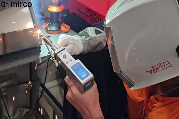 یک اپراتور صنعتی در حال استفاده از دستگاه جوش لیزر دستی برای اتصال دو قطعه استنلس استیل با دقت بالا