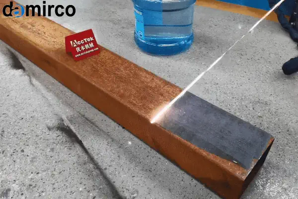 یک اپراتور صنعتی در حال کار با دستگاه زنگ زدای لیزری روی یک قطعه فلزی