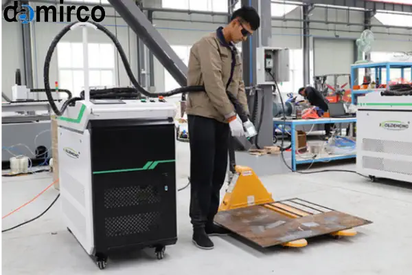 یک دستگاه زنگ زدای صنعتی در حال تمیز کردن سطح یک قطعه بزرگ فلزی در کارخانه