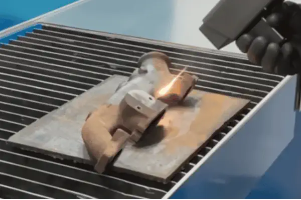 یک دستگاه زنگ زدای صنعتی در حال آماده سازی سطح یک قطعه فلزی بزرگ