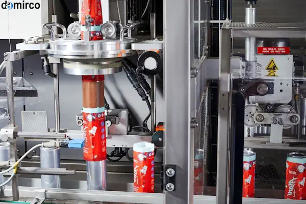 دستگاه لیبل شیرینگ برای ظروف پت در یک خط تولید نوشیدنی در حال لیبل زنی بطری‌ها